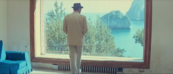 Movie still from “Contempt” (1963), directed by Jean-Luc Godard – A man wearing a suit and hat looking out of a window; Wide shot, Low angle