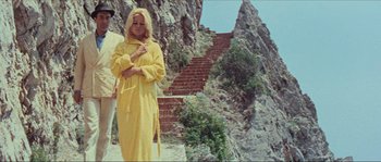 Movie still from “Contempt” (1963), directed by Jean-Luc Godard – A woman in a yellow robe standing next to some steps; Medium shot, Low angle