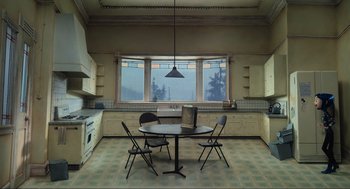 Movie still from “Coraline” (2009), directed by Henry Selick – An empty kitchen with a table , chairs , and a laptop; Extreme Wide shot, High angle