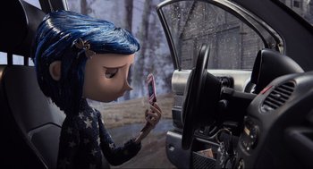 Movie still from “Coraline” (2009), directed by Henry Selick – A person holding a cell phone in their hand; Medium shot, Over the shoulder angle