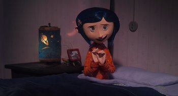 Movie still from “Coraline” (2009), directed by Henry Selick – A doll is sitting on a bed with a clock in the background; Medium shot, Overhead angle