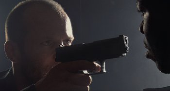 Movie still from “Crank” (2006), directed by Mark Neveldine – A person holding a gun in his hand; Close Up shot, Low angle