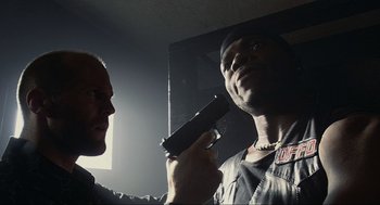 Movie still from “Crank” (2006), directed by Mark Neveldine – A man holding a gun up to a man's face; Close Up shot, Low angle