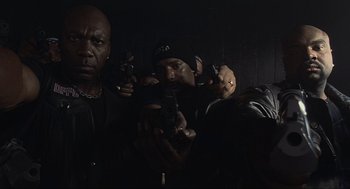 Movie still from “Crank” (2006), directed by Mark Neveldine – A group of men holding guns in a dark room; Medium shot, Low angle