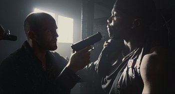 Movie still from “Crank” (2006), directed by Mark Neveldine – Two men are holding guns in a dark room; Medium shot, Low angle