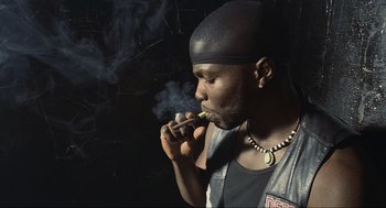 Movie still from “Crank” (2006), directed by Mark Neveldine – A man smoking a cigarette while wearing a leather vest; Close Up shot, Low angle