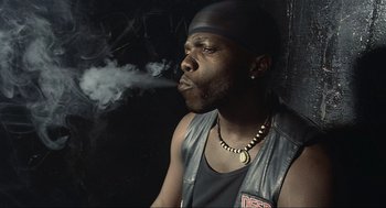 Movie still from “Crank” (2006), directed by Mark Neveldine – A man in a leather vest smoking a cigarette; Close Up shot, Low angle