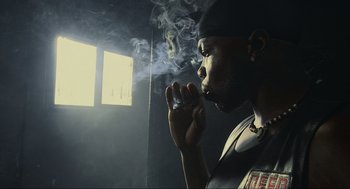 Movie still from “Crank” (2006), directed by Mark Neveldine – A man smoking a cigarette in a dark room; Close Up shot, Low angle
