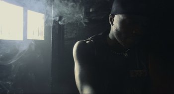 Movie still from “Crank” (2006), directed by Mark Neveldine – A man smoking a cigarette in a dark room; Close Up shot, Low angle