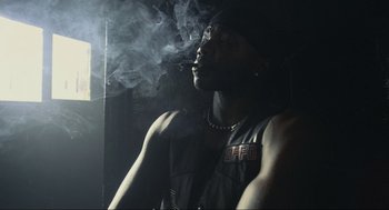 Movie still from “Crank” (2006), directed by Mark Neveldine – A man smoking a cigarette in a dark room; Close Up shot, Low angle