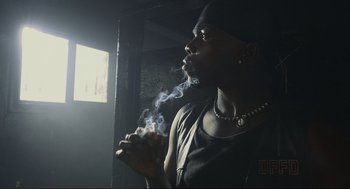 Movie still from “Crank” (2006), directed by Mark Neveldine – A man smoking a cigarette in a dark room; Close Up shot, Low angle