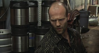 Movie still from “Crank” (2006), directed by Mark Neveldine – A bald man with a beard and a black shirt; Close Up shot, Low angle