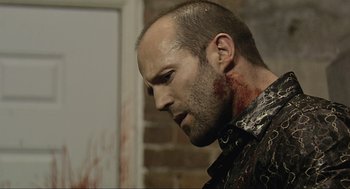 Movie still from “Crank” (2006), directed by Mark Neveldine – A person with blood on his face; Close Up shot, Over the shoulder angle