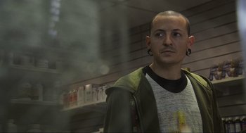 Movie still from “Crank” (2006), directed by Mark Neveldine – A man standing in front of a store window; Close Up shot, Over the shoulder angle