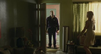 Movie still from “Crank” (2006), directed by Mark Neveldine – A man standing in front of an open door; Wide shot, Low angle