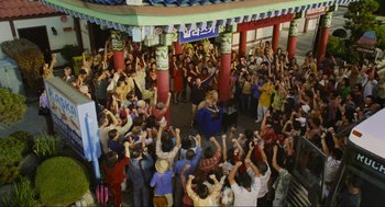 Movie still from “Crank” (2006), directed by Mark Neveldine – A crowd of people standing around a building with their hands up; Wide shot, High angle