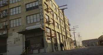 Movie still from “Crank” (2006), directed by Mark Neveldine – A man walking down the street in front of a building; Extreme Wide shot, Low angle