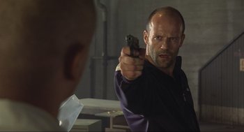 Movie still from “Crank” (2006), directed by Mark Neveldine – A man holding a gun in front of a mirror; Close Up shot, Over the shoulder angle