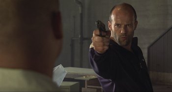 Movie still from “Crank” (2006), directed by Mark Neveldine – A man holding a gun in front of a mirror; Close Up shot, Over the shoulder angle