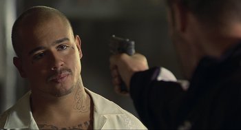 Movie still from “Crank” (2006), directed by Mark Neveldine – A man holding a gun pointed at a man with a tattoo; Close Up shot, Over the shoulder angle