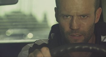 Movie still from “Crank” (2006), directed by Mark Neveldine – A person driving a car; Close Up shot, Over the shoulder angle
