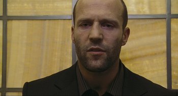 Movie still from “Crank” (2006), directed by Mark Neveldine – A man in a suit and tie looking at the camera; Close Up shot, Low angle