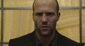 Movie still from “Crank” (2006), directed by Mark Neveldine – A man with a bald head wearing a suit and tie; Close Up shot, Low angle
