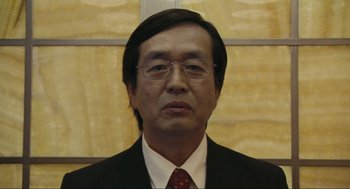 Movie still from “Crank” (2006), directed by Mark Neveldine – A person wearing a suit and tie; Close Up shot, Low angle