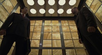Movie still from “Crank” (2006), directed by Mark Neveldine – Two men standing in front of each other in front of a wall of lights; Wide shot, Low angle