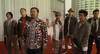 Movie still from “Crank” (2006), directed by Mark Neveldine – A group of men standing next to each other on a red carpet; Medium shot, Low angle