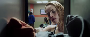 Movie still from “Crawl” (2019), directed by Alexandre Aja – A woman sitting in front of a television in a room; Close Up shot, Over the shoulder angle