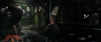 Movie still from “Crawl” (2019), directed by Alexandre Aja – A man sitting on the ground in a dark room; Wide shot, Overhead angle