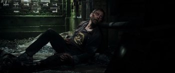 Movie still from “Crawl” (2019), directed by Alexandre Aja – A man sitting on the ground in the middle of the night; Medium shot, Overhead angle