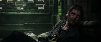 Movie still from “Crawl” (2019), directed by Alexandre Aja – A man sitting on the ground in a dark room; Medium shot, Over the shoulder angle