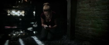Movie still from “Crawl” (2019), directed by Alexandre Aja – A woman sitting on the ground looking at her cell phone; Medium shot, High angle