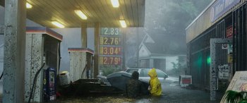 Movie still from “Crawl” (2019), directed by Alexandre Aja – Two people sitting in the pouring rain at a gas station; Extreme Wide shot, High angle