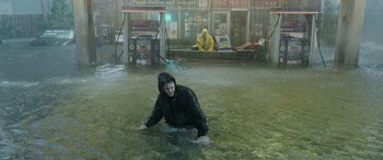 Movie still from “Crawl” (2019), directed by Alexandre Aja – A man in a raincoat is wading through a flooded street; Wide shot, High angle