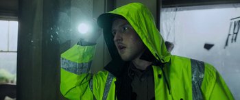 Movie still from “Crawl” (2019), directed by Alexandre Aja – A man in a yellow rain jacket holding up a flashlight; Close Up shot, Low angle