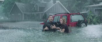 Movie still from “Crawl” (2019), directed by Alexandre Aja – A man and a woman holding a dog in a flooded area; Wide shot, High angle