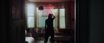 Movie still from “Crawl” (2019), directed by Alexandre Aja – A woman standing in a flooded living room holding a spray bottle; Wide shot, High angle