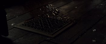 Movie still from “Crawlspace” (2022), directed by L. Gustavo Cooper – A computer keyboard sitting on top of a wooden floor; Extreme Close Up shot, Overhead angle
