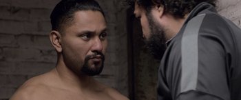 Movie still from “Creed” (2015), directed by Ryan Coogler – A man standing next to another man with a beard; Close Up shot, Over the shoulder angle