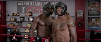 Movie still from “Creed” (2015), directed by Ryan Coogler – Two boxers pose for a picture in a boxing gym; Medium shot, Over the shoulder angle