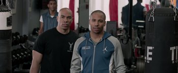 Movie still from “Creed” (2015), directed by Ryan Coogler – Two young men standing next to each other in a gym; Medium shot, Over the shoulder angle