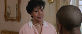 Movie still from “Creed” (2015), directed by Ryan Coogler – An older woman wearing a pink shirt and a pearl necklace; Close Up shot, Over the shoulder angle