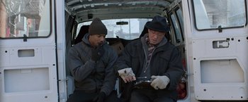 Movie still from “Creed” (2015), directed by Ryan Coogler – Two men sitting in the back of a van looking at a tablet computer; Medium shot, Over the shoulder angle