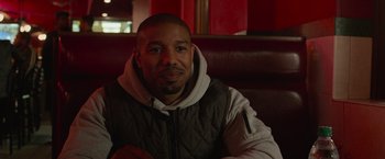 Movie still from “Creed” (2015), directed by Ryan Coogler – A person sitting on a couch; Close Up shot, Over the shoulder angle