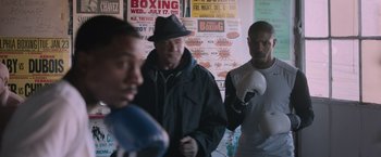 Movie still from “Creed” (2015), directed by Ryan Coogler – A group of men standing next to each other in a room; Medium shot, Over the shoulder angle