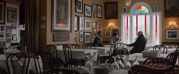Movie still from “Creed” (2015), directed by Ryan Coogler – Two men sitting at a table in front of a bunch of pictures; Wide shot, Over the shoulder angle