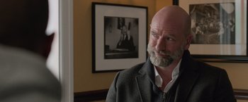 Movie still from “Creed” (2015), directed by Ryan Coogler – A man with a beard standing in front of a picture; Close Up shot, Over the shoulder angle